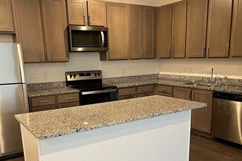 A kitchen with a granite countertop and stainless steel appliances.